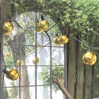 gold bauble festoon lights positioned in front of a mirror