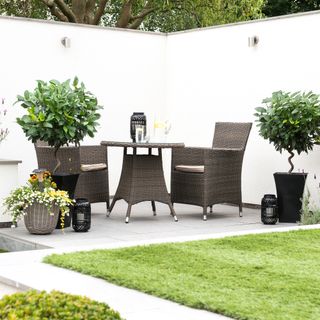 Garden with dining set on tiled patio area surrounded by white walls with spotlights